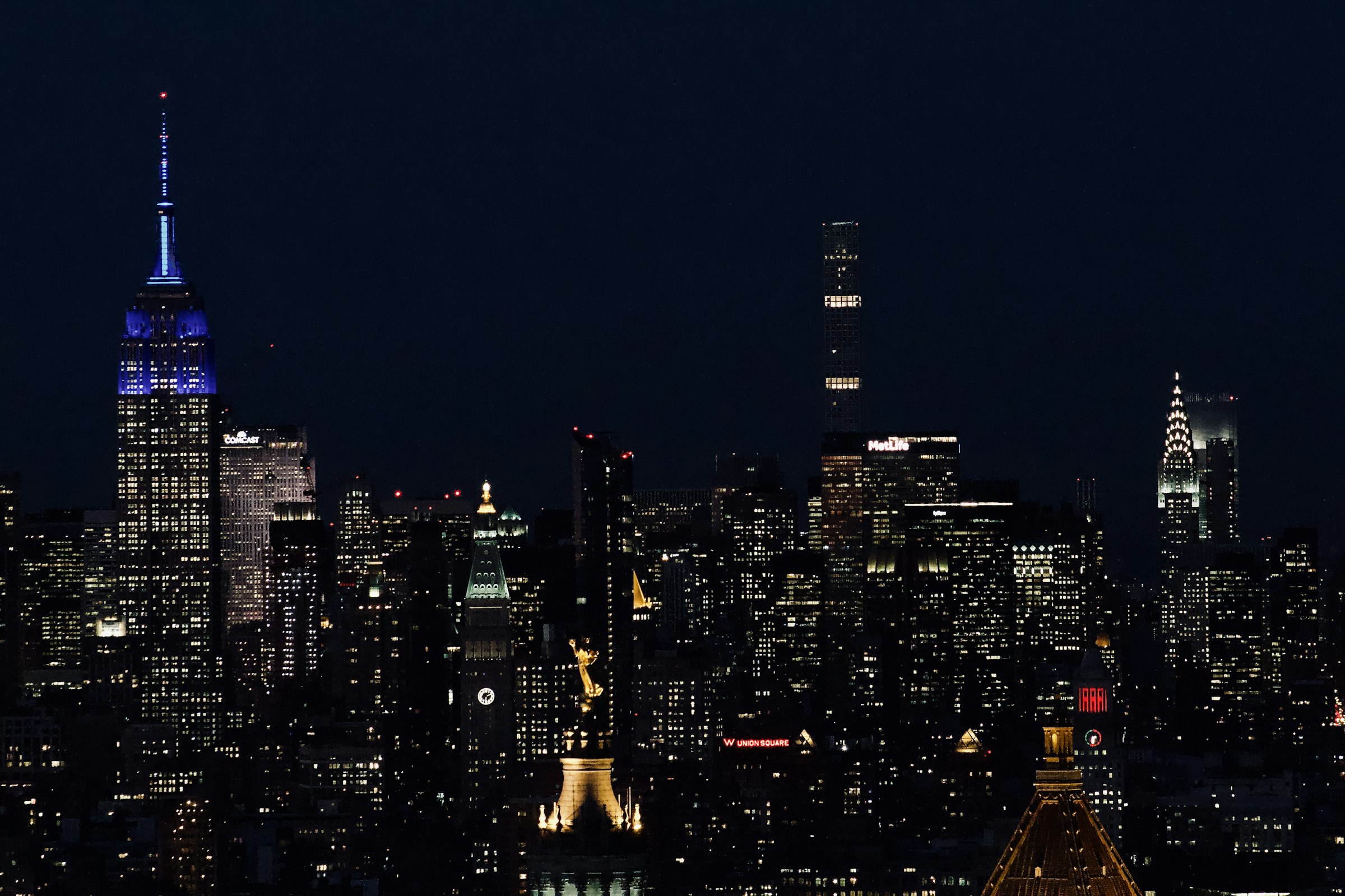 Midtown Manhattan just after dusk: the Empire State Building and the Chrysler Building lit against a dark sky.